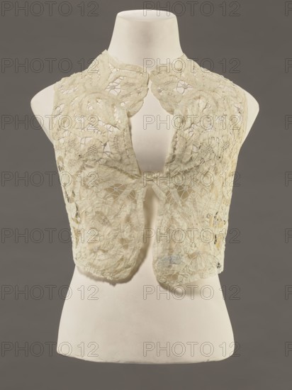 Bodice, lace;, Pattern of rosettes connected by large spiders and heads; pattern of stylized floral motifs. 19th century, France. Women's clothing; clothing accessory. Height 36 cm; circumference 63 cm., A cream-colored lace vest displayed on a white torso mannequin against a gray background, showing intricate floral and circular lace patterns with openwork, scalloped edges at the neckline, and a soft, slightly aged texture in the lace; the mannequin is smooth and off-white, and the backdrop is a muted mid-gray.