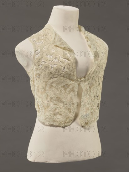 Bodice, lace; bodices, women's clothing, fashion. In a pattern of rosettes connected by large spiders and heads. Pattern of stylized floral motifs. 19th century, France. Clothing accessory. Height 36 cm, circumference 63 cm., Provenance unknown., A mannequin torso in off-white displays a sleeveless lace vest in a pale cream color with an open front and scalloped edges; the lace features floral and circular patterns with areas of sheer openwork, and the background is a solid dark gray.