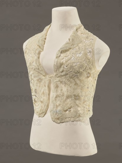 Bodice, lace, provenance unknown, bodices, women's clothing, fashion. In a pattern of rosettes connected by large spiders and heads; pattern of stylized floral motifs. 19th century, France. Clothing accessory. Height 36 cm, circumference 63 cm., A dress form in off-white displays a sleeveless lace vest in pale cream with intricate openwork floral and circular patterns, scalloped edges, and a soft drape at the neckline; the background is a solid muted gray-brown.