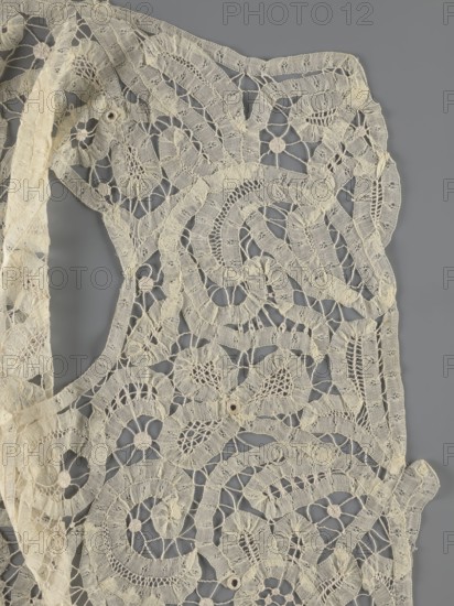 Bodice, lace, bodices, women's clothing, fashion. In a pattern of rosettes connected by large spiders and heads; pattern of stylized floral motifs. 19th century, France. Clothing accessory. Height 36 cm, circumference 63 cm., A section of delicate openwork lace in a pale off-white tone lies against a smooth neutral gray background, showing an intricate pattern of swirling motifs and floral-like shapes created by interlacing threads and open mesh; the lace includes scalloped and curved bands, small circular rosettes, and areas of denser woven texture contrasting with airy netted sections, with subtle variations in the off-white color and slight shadowing where the fabric overlaps or folds.