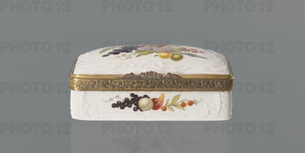 Snuffbox tin, Koenigliche Porzellan Manufaktur KPM; Berlin; 1763-1918 manufacturer, flowers, fruit, snuffboxes, miniatures. Snuffbox in the form of a rectangular box with a slightly arched lid, framed in gilded bronze, with a plant ornament around the outer edge of the lid and a lock, on hinges. Around the edge of the lid and the side walls of the tin there is a relief with rocaille and floral motifs. On the lid, the bottom of the base and each of the side walls a colorful fruit and floral composition including blackcurrant, fig, mirabelle plum or redcurrant and plums. On the inside of the lid there is a colorful composition with a bouquet of flowers in a cup-shaped brown vase on a stone tabletop with fruit and a sprig of raspberry flowers; on the edge of the tabletop a small bird sparrow? nibbling a leaf, above two butterflies flying. ca. 1765–1770. Germany, Berlin. Porcelain haberdashery snuffbox. Height 3.2 cm; width 8.3 cm; depth 6 cm., A small rectangular decorative box sits again...