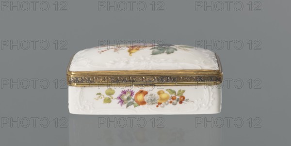 Snuffbox tin, Koenigliche Porzellan Manufaktur KPM; Berlin; 1763–1918. Snuffbox in the form of a rectangular box with a slightly arched lid, framed in gilded bronze, with a plant ornament around the outer edge of the lid and a lock, on hinges. Around the edge of the lid and the side walls of the tin there is a relief with rocaille and floral motifs. On the lid, the bottom of the base and each of the side walls are painted with colorful fruit and floral compositions including blackcurrant, fig, mirabelle plum or redcurrant and plums. Inside the lid is a painted composition of a bouquet of flowers in a cup-shaped brown vase on a stone tabletop with fruit and a sprig of raspberry flowers; on the edge of the tabletop a small bird sparrow? nibbling a leaf, above two butterflies flying. Ca. 1765–1770. Porcelain haberdashery snuffbox. Germany, Berlin. Height 3.2 cm; width 8.3 cm; depth 6 cm., A small rectangular trinket box sits centered against a gray background, with a white porcelain body ...