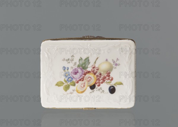 Snuffbox tin, Koenigliche Porzellan Manufaktur KPM; Berlin; 1763–1918. Snuffbox in the form of a rectangular box with a slightly arched lid, framed in gilded bronze, with a plant ornament around the outer edge of the lid and a lock, on hinges. Around the edge of the lid and the side walls of the tin there is a relief with rocaille and floral motifs. On the lid, the bottom of the base and each of the side walls: colorful fruit and floral compositions including blackcurrant, fig, mirabelle plum or redcurrant, and plums. Inside the lid: a colorful composition with a bouquet of flowers in a cup-shaped brown vase on a stone tabletop with fruit and a sprig of raspberry flowers; on the edge of the tabletop a small bird sparrow? nibbling a leaf, above two butterflies flying. Ca. 1765–1770. Porcelain haberdashery snuffbox. Germany; Berlin. Height 3.2 cm, width 8.3 cm, depth 6 cm., A rectangular white porcelain box with embossed decorative borders sits against a gray background, showing a painte...