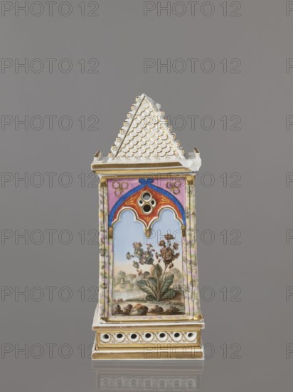Night Lamp, Popow, Alexander porcelain manufacturer; 1806–1872 author, lamps, landscapes with architecture, neo-Gothic style, plant motifs. Lamp composed of three parts: base, lamp, and cover. Base with a horizontal row of holes on each side creating a decorative trail. Lamp in the form of a cube, in the neo-Gothic style; on the arcades in the shape of a tracery painted colorful landscapes: two with motifs of flowering bushes primrose and jasmine, floral motifs against the background of a landscape, two landscapes with an architectural motif. 19th century, Russia, Gorbunovo. Height 32.2 cm, width 13 cm., A tall, narrow decorative object with a pointed, white roof textured with a scale pattern and gold accents sits against a plain gray background; below the roof is a band with gold trim above a front panel framed by vertical borders patterned in pale green and pink, the top of the panel showing an arch design in blue, red, pink, and gold with a small circular opening, and the main panel...