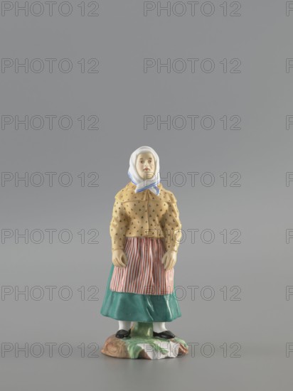 Figurine: Peasant Woman, Popov, Alexander porcelain factory; 1806–1872,  factory author, figurines. Figurine depicting a woman in a white scarf with a blue border on her head, wearing a green skirt and apron with red stripes, a yellowish caftan with black dots. Base missing. 1830–1840, Russia, Gorbunovo. Figurine; height 3.5 cm, width 6.0 cm, depth 5.7 cm., A porcelain figurine of a standing woman wearing a white headscarf with blue trim, a yellow patterned jacket, a red and white striped apron, and a teal skirt, with white stockings and black shoes, positioned on a multicolored base with green, brown, and white areas; the background is a uniform gray.