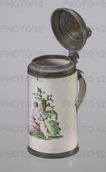 Cylindrical tankard in a pewter frame, Prószków Slaski faience factory; 1763–1853. White, painted in colors. From the front, a depiction of a barefoot woman sitting under a tree, her blouse unbuttoned revealing her breasts. The woman, head turned to the right, supports with her right hand a small child, dressed in a short T-shirt, running towards her from the left. It can be interpreted as an allegorical representation of Maternitas motherhood. The representation is painted with some freedom. Late 18th century, Silesia Province of Silesia. Vessel; height 24.0 cm, width 15.0 cm, depth 10.5 cm., A ceramic tankard with a hinged metal lid is shown against a pale gray background; the tankard is mostly white with metal rim and base in a dull gray, and a matching metal lid that is open, showing the interior metallic surface. The body features a painted scene in soft colors including green, pink, blue, yellow, and flesh tones depicting a seated woman and a child by a tree with foliage and gras...
