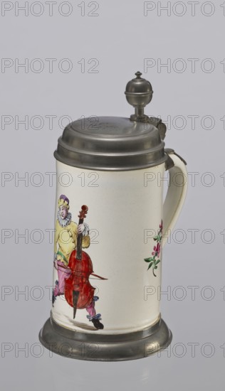 Tin-mounted tankard, Prószków Slaski faience factory 1763–1853. White cylindrical tankard in a pewter mount. On the front is a depiction of an obese musician playing a double bass, shown in vigorous movement. The musician wears a yellow jacket, purple pantaloons, and a lilac hat with a yellow brim. Floral sprigs on the sides. On the tin cover engraved CGH/1811. Late 18th century. Province of Silesia 1742–1918; Silesia; Prószków Slaski. Vessel. Height 24.0 cm; width 15.0 cm; depth 9.5 cm., A ceramic stein with a metal lid and base, mostly cream colored with painted decoration, shows a painted figure wearing a yellow top, pink pants, purple and yellow headwear, and black shoes while holding a red stringed instrument, with additional small floral motifs in green and pink on the body; the lid, hinge, thumbpiece, and base are metallic gray, and the handle is the same cream color as the stein.