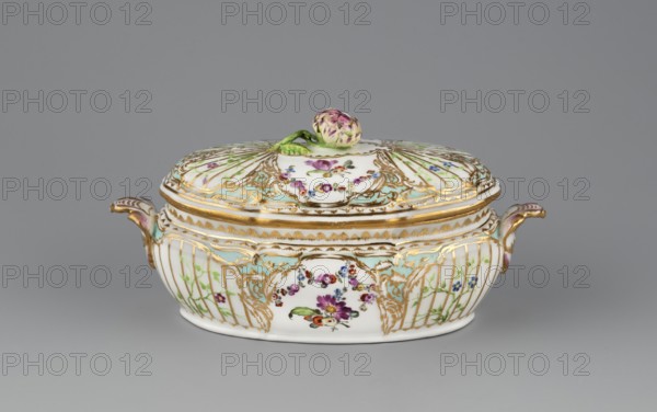 Vase with a lid, with Reliefzierat decoration, Koenigliche Porzellan Manufaktur KPM ; Berlin ; 1763-1918 manufacturer, Frederick II the Great King of Prussia ; 1712-1786, Reliefzierat, rocaille ornament, Oval vase with a distinct narrow rim around the edge and base, with rocaille handles; around the bowl a relief with a trellis of gilded stamens with an interwoven green branch with small flowers Reliefzierat, in two fields on both longer sides of the vase, separated by gilded rocailles with celadon backgrounds, and in the middle with a colourful floral decoration of garlands and a bouquet. Gilded edges and handles. Analogous decoration on the lid, radial, in a four-part arrangement; handle a plastic flower with a branch. ca. 1770/1780, Berlin, Germany; vessel, vase., An oval porcelain covered dish with a domed lid and a decorative knob shaped like a flower bud sits against a plain gray background; the dish is predominantly white with extensive gold-painted scrollwork and edging, pale g...