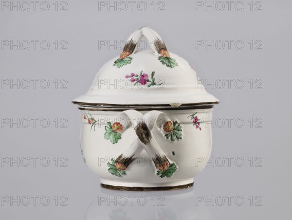 Vase with lid, Prószków Slaski faience factory; 1763–1853, floral decorations, soup tureen, roses, provenance repossession. Egg-shaped soup tureen with a lid in the form of a flattened ellipsoid/hemisphere. Handles of the vase and lid are two crossed ribbons. Decorated with small painted floral sprigs and large bouquets of multicolored flowers; on both sides of the vase and lid are bouquets with a pink rose. Handles adorned with vermilion daisies with large green leaves. Rim of vase and cover painted brown. Circa 1785. Province of Silesia 1742–1918, Silesia, Prószków Slaski. Vessel; height 25.5 cm, length 35.5 cm., A white ceramic lidded vessel with a rounded body and a domed lid topped by a looped handle, decorated with painted floral motifs in green, pink, and orange, and accented with brown brushstrokes on the handles and rim; the piece rests on a short base and sits against a pale gray background.
