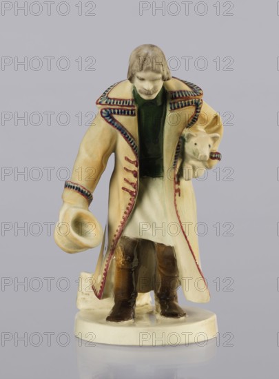 Peasant with Piglet, First Galician Factory of Artistic Faience and Terracotta Pacyków; 1912–1939 manufacturer, Popiel, Antoni 1865–1910 sculptor. Figurine of a man in a peasant Hutsul russet coat, on a circular base. The peasant, with straight-cut hair and a period mustache, stands slightly bowed, holding a hat in his right hand and a piglet under his left arm. At the back on the base is a woven basket. Warm tones: light ochre russet coat with brown-purple trim; underneath a green vest, dark trousers, and brown shoes. Circa 1910. Pacyków. Terracotta/faience figurine. Height 14.5 cm; width 8.0 cm; depth 5.5 cm., A ceramic figurine of a person wearing a long coat with decorative trim, holding a hat in one hand and a small animal in the other, standing on an oval base; the figure shows a pale face and brown hair, a dark green garment under the coat, the coat and base are cream or beige with red and blue trim details, the small animal is light-colored, and the boots are brown, all set aga...