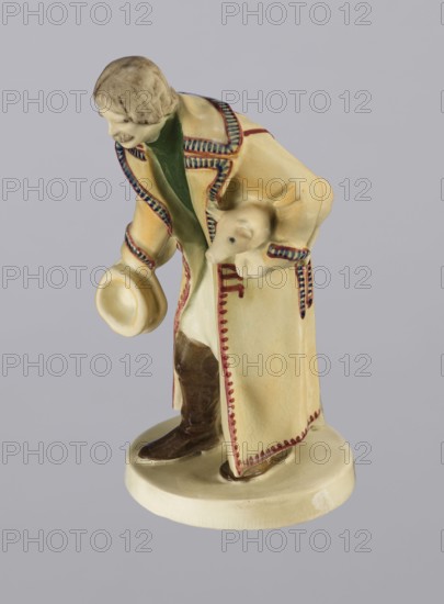 Peasant with Piglet, First Galician Factory of Artistic Faience and Terracotta Pacyków; 1912–1939 manufacturer, Popiel, Antoni 1865–1910 sculptor. Figurine of a man in a peasant Hutsul russet coat, on a circular base. The peasant, with straight-cut hair and a period mustache, stands slightly bowed, holding a hat in his right hand and a piglet under his left arm. A woven basket is on the base at the back. Warm tones: light ochre russet coat with brown-purple trim; underneath a green vest, dark trousers, and brown shoes. Circa 1910, Pacyków. Terracotta figurine; height 14.5 cm, width 8.0 cm, depth 5.5 cm., A ceramic figurine of a person wearing a long coat and holding a hat, with a small animal tucked under one arm, standing on a rounded base; the coat is primarily cream with decorative trim in red and blue, the interior of the coat shows a green area, the hat and base are cream, the person’s hair is a muted brownish-gray, the boots are dark brown, and the small animal is cream with a sl...