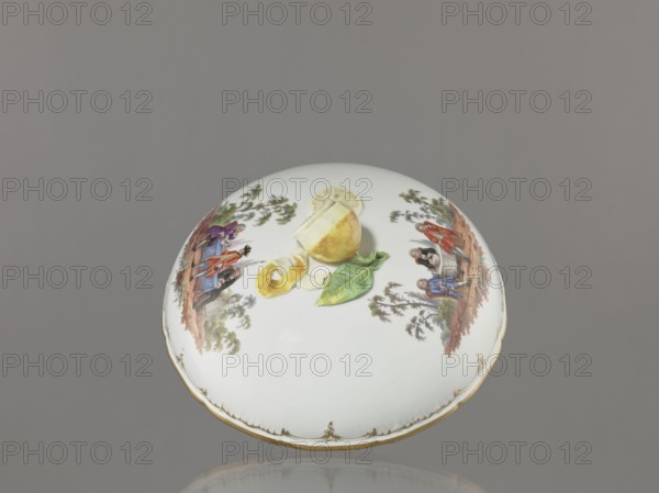 Punch Vase with Lid, Königliche Porzellan-Manufaktur KPM, reliefs, genre miniatures. Vase with a hemispherical bowl, bottom rim, and arched circular lid with a handle modeled as a half-peeled lemon with stem, leaf, two slices, and rolled-up peel. Rim of vase and lid with relief rocaille decorations, gilded. Two color miniatures on the lid park scenes: 1 three men in 18th-century costume seated at a table with a vase and glasses; 2 three men at a table, one standing. Two color miniatures on the bowl park settings: 1 six people at a round table with glasses and pipes, one figure reclining in front of the table; 2 seven people at a table singing, smoking pipes, and talking. Possibly after engravings by W. Hogarth. 4th quarter of the 18th century, Berlin, Germany. Vase; height 27.5 cm, width 28 cm., A round white porcelain lid with a glossy finish sits against a gray background, decorated with painted scenes of people in period clothing in earthy tones and a few green trees, a painted yell...