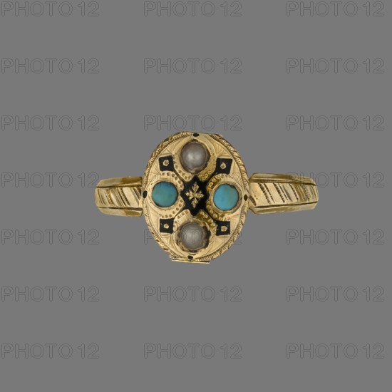 Ring by Romain Doreau fl. 1848–1863, jeweler. Oval gold ring with a band that widens slightly and features diagonal notches. The bezel is divided by strips of black enamel into four fields, each set with two alternating turquoise stones and two half-pearls. Along the ring’s underside is a tube with an oculus containing nine visible portrait photographs from the 1850s. Materials: gold, enamel, turquoise, pearls, photographs. Style: mid-19th century French jewelry. Dimensions: height 1.2 cm; width 2 cm; depth 2.2 cm., A gold ring with an oval top set with a symmetrical arrangement of round stones and decorative details; the top shows a group of four raised round stones with two turquoise-blue stones opposite each other and two greyish-white stones opposite each other, surrounding a small central black decorative element with gold detailing; the gold surface around the stones has engraved patterns and small black accents, and the band has diagonal engraved lines; visible colors include go...