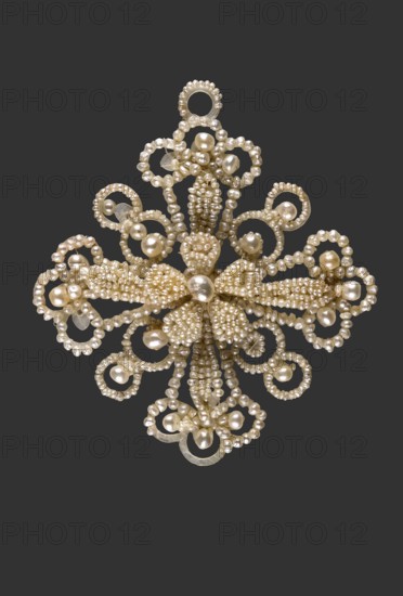 Pendant in the shape of a four-leaf rosette; pearls glued to an openwork mother-of-pearl body. Each of the four arms ends in a trefoil, with four elongated oval leaves superimposed on each, above which is a five-leaf rosette. One arm has an additional ring for attaching a suspension separate. Early 1st third of the 19th century, Great Britain/England . Jewelry, clothing accessory/rosette/women's ornament. Weight 7.3 g; height 5.6 cm; width 5.1 cm. Makers/author, ., A decorative brooch-like object composed of numerous small round beads and larger oval beads arranged in an ornate symmetrical floral and looped pattern against a solid dark gray background, with the beads appearing pearly and off-white to cream in color and a few elements showing a slightly translucent or reflective sheen.