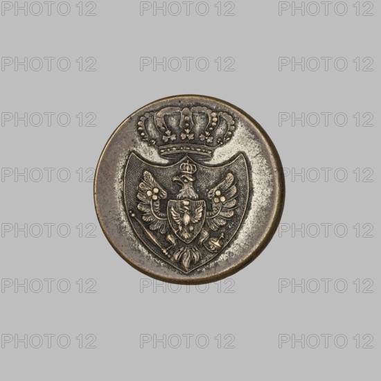Official's uniform button, Grand Duchy of Poznan coat of arms, clothing accessory; on the obverse, in a cartouche under a crown, a Prussian Eagle under a crown holding a scepter and an orb, with the Polish Eagle in a heart shield; on the reverse, in the rim, a crown and the German inscription FÜR KÖNIG UND VATERLAND; ca. 1848; Germany, possibly Berlin; diameter 2.1 cm., A round metallic medallion with a raised heraldic design sits against a flat grey background; the medallion shows a crowned shield containing a stylized double-headed eagle with spread wings, floral or rosette details on the wings, a smaller shield on the eagle's chest, and ornamental elements beneath the eagle, all rendered in worn metallic tones of bronze, brass, and dark patina with areas of lighter silver-like wear.