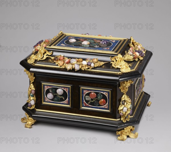 Jewel box, pietra dura technique. Jewel box made of blackened wood, partly ebony, cuboid with chamfered corners supported on four gilded bronze volute legs decorated with a mascaron at the base. The edge of the base and the edge of the lid have profiled ebony strips. Decorated on the side walls with six mosaic reserves and one plaque on the lid. On the front and back two panels depict two fruits on a branch; on the sides one panel each shows three fruits on a branch and an insect at the bottom. Corners bear cast gilded bronze garlands topped with medusa masks decorated with plastic fruits made of semi-precious stones 7 pieces each. The hinged, profiled lid is decorated with a large plate with three fruits on branches tied with a sash, above them an insect; side walls feature gilded bronze garlands with plastic fruits; corners have gilded bronze shells; the front has a preserved key hole. Dated to the early 18th century 18th century, Florence?, Italy?. Chest. Height 34.5 cm, width 41.5 ...