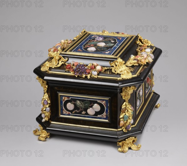 Jewel box, pietra dura technique. Jewel box made of blackened wood, partly ebony, cuboid with chamfered corners supported on four gilded bronze volute legs decorated with a mascaron at the base. The edge of the base and the edge of the lid have profiled ebony strips. Decorated on the side walls with six mosaic reserves and one plaque on the lid: on the front and back two panels decorated with two fruits on a branch; on the sides one panel each with three fruits on a branch and an insect at the bottom. In the corners are cast gilded bronze garlands topped with medusa masks decorated with plastic fruits made of semi-precious stones 7 pieces each. The hinged, profiled lid is decorated with a large plate with three fruits on branches tied with a sash, above them an insect; side walls decorated with gilded bronze garlands with plastic fruits; corners with gilded bronze shells; front with a preserved key hole. Dated to the early 18th century 18th century, possibly Florence, Italy. Chest, hei...