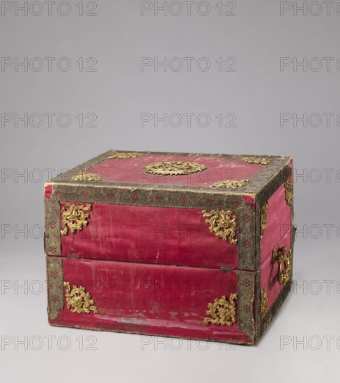 Casket case, gift, Maria Kazimiera Queen of Poland; 1641–1716, Strzalecki, Antoni Jan 1844–1934. The case is a rectangular wooden box covered with red velvet, with gold thread trimmings on the edges. The crosspieces have bronze openwork overlays. The side walls have gilded bronze handles; the top has a decorative central overlay with a rank crown. The front has a decorative overlay serving as a lock plate; the keyhole is preserved. The interior is lined with light green silk. Early 19th century; 18th century, Italy, Florence. Chest; height 39.5 cm, width 56.7 cm, depth 47.5 cm., A rectangular wooden box covered in red fabric with a worn surface and trimmed with dark textured edging; a group of ornate gold decorative metal appliques adorn the corners and center of the top and sides, and there are a few gold ring handles on the visible side; the box shows signs of wear with scuffs and faded areas on the red fabric, and the background is a smooth neutral gray.