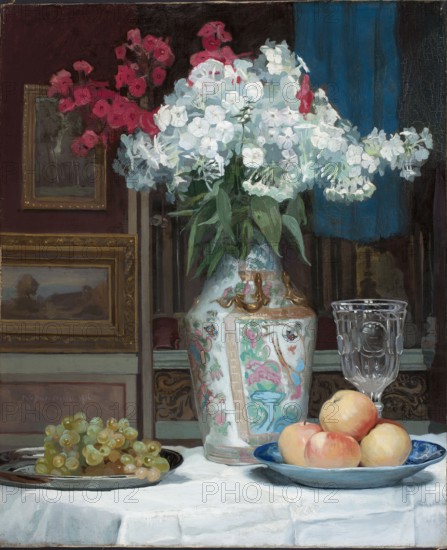 Still Life with a Bouquet of Phloxes, Krasnodebski, Piotr Hipolit 1876–1928 painter, realism style, phloxes, apples, grapes, fruit still life with flowers, pictures within pictures, Chinese vase, 1916, oil on panel?, picture, height 70 cm, width 57 cm, A still life showing a large ornate vase with floral designs holding a bouquet of white flowers with green leaves and a few clusters of pink flowers behind them, set against a dark background with a blue vertical cloth; to the right of the vase there is a clear glass goblet and a blue plate holding several round fruits with peach and yellow tones, and to the left there is a dark dish piled with a group of greenish-yellow grapes, all arranged on a white tablecloth with subtle folds.
