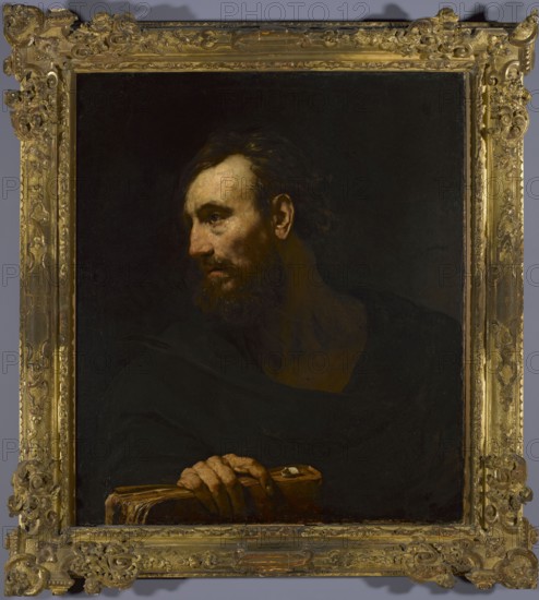 Old Man with a Book, Drost, Willem 1633-1659 painter, Dutch painting, Italian painting, busts, book attribute, 1654–1659, painting, height 86 cm, width 74 cm, A framed oil painting showing a bearded man in three-quarter profile turned to his left, with pale skin and dark brown hair and beard, wearing dark clothing that blends into a black background; his face and hand are illuminated, revealing flesh tones and subtle reddish-brown and ochre highlights, and his fingers rest on a worn brown book with a lighter tan edge; the ornate frame around the painting is gilded gold with decorative carved patterns, and the overall visible colors include black, dark brown, pale skin tones, reddish-brown, ochre, tan, and gold.