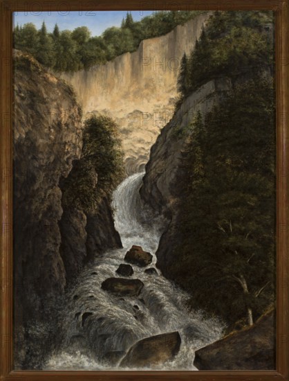 Mountain Waterfall in St. Gervais, Cyprian Lachnicki 1824–1906, painter; end of 19th century; oil painting; dimensions: height 151.5 cm, width 112.5 cm; with frame: height 175 cm, width 134 cm, thickness 10 cm; Young Poland style., A framed landscape painting showing a steep rocky gorge with a cascading waterfall flowing toward the foreground, dark wet rocks and boulders interrupting the rushing water; dense foliage and trees line the sides of the gorge, with a mix of deep greens and muted olive tones, and lighter green highlights on some tree crowns; the cliff faces show earthy browns, ochre, and gray rock textures; the waterfall and foamy water display shades of white, gray, and silvery highlights; the upper background reveals a pale blue sky above a line of darker green treetops; the frame around the painting is a warm brown wood color.