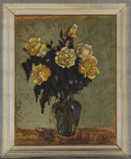 Tea roses in a green vase; Jan Bohuszewicz 1878–1935, painter; contemporary painting; flowers, still life; interwar period; painted 1933; possibly Italy; oil painting; 64 × 51 cm., A framed painting of a vase holding a bouquet of flowers; the frame is off-white with a slightly weathered look. The background is a muted green with textured brushstrokes. The vase is dark green with reflective highlights and sits on a brownish surface. The flowers are predominantly yellow with touches of white and warm orange tones, and the foliage and stems are rendered in very dark green to nearly black, creating strong contrast with the blooms. The overall palette includes greens, yellows, browns, off-white, black, and hints of orange.