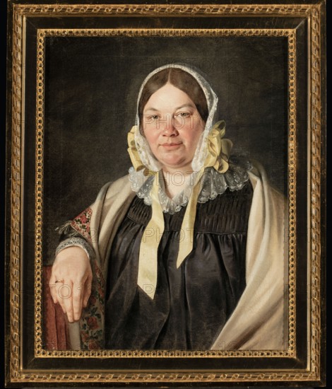 Portrait of Aleksandra Bebnowska, née Cybulska, the painter's mother-in-law; Jan Chrucki 1810–1885, painter; ca. 1845; oil painting; female half-length seated portrait, full-face; Biedermeier style; depiction includes scarf, bonnet, wedding ring., A painted portrait of a seated woman wearing a white lace bonnet with yellow ribbons, a dark dress, and a light shawl draped over one shoulder, her hand resting on a patterned armrest; her face is fair with brown hair, and the background is dark, all set inside an ornate gold frame showing tones of gold and black.