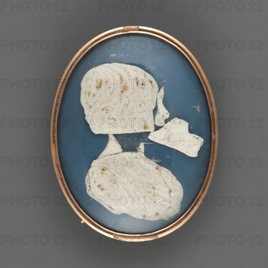 Profile bust of a boy priest Sanguszko?, Krzeszowice Lesser Poland Voivodeship, ruins, boys, silhouettes, profiles portraits, amateurs, 1750, miniature, height 4.6 cm, width 3.6 cm, An oval object with a thin metallic gold-colored frame surrounds an inner oval field of deep blue; within the blue field are a few irregular white paper-like shapes arranged to suggest a head in profile and upper torso, the white shapes showing a few small brownish spots and some faint textured marks, while the background around the shapes is blue with small areas of wear; the outer area surrounding the framed oval is a flat medium gray.