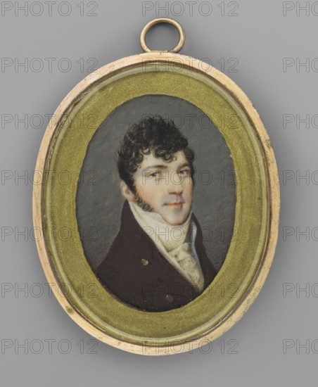 Portrait of a Young Man, Auvigny, Charles d' 1760–1830 painter; portrait en trois-quarts of a man; Polish miniature; 1823; miniature, height 4.9 cm, width 3.8 cm. Bust 3/4 right; black hair with short curls at temples and forehead, curly sideburns, bluish shadow of shaved beard around the mouth. Clothing: white collar, cravat and pleated jabot, white waistcoat, brown tailcoat with gold buttons. Background off-grey. Around the miniature a paper border painted with gold paint. Narrow oval frame made of gilded bronze. Poland place of origin., An oval painted portrait of a man set in a small oval frame with a loop at the top, the frame showing a metallic gold color with a textured inner border and a lighter gold outer rim, against a neutral gray background; the portrait shows a man with dark curly hair and sideburns, pale skin, and dark eyes, wearing a dark brown coat and a white high-collared shirt with a light-colored cravat, the painted background behind him being a muted gray.