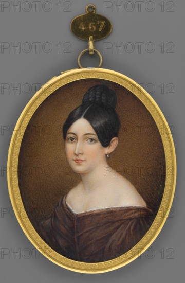 Portrait of a Young Woman in a Brown Dress, Krüger, Franz 1797–1857 painter; portraits below the shoulders; portraits of women 3/4 left; young woman; dresses corseted; hairstyle parted above the forehead with chignon; foreign miniatures; bust 3/4 left; black hair; chignon; brown eyes; pearl earring in one ear; brown dress with narrow white lace ruffle, deeply corseted; background rusty brown; binding: narrow gilt bronze rim with palmette motif all around; 1852; Germany; miniature; height 7.2 cm, width 5.9 cm, An oval painted miniature of a woman set in a gold frame with a small metal loop and tag at the top, showing a woman with dark hair styled in a high bun and sleek front sections, pale skin, and neutral facial expression; she wears a dark off-the-shoulder garment with a lighter trim and a single small earring, set against a textured brown background within the gold border, and the surrounding background outside the frame is gray.