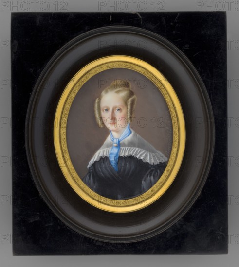 Portrait of Mrs. Ordezyna? Antonina née Kielczewski 1811–1893, wife of Józef Ordega, Lodzia coat of arms 1802–1879. Painted by Leon Brzezinski 1809–1865. Female portrait, three-quarters, young woman, half-length, almost straight posture, light blond hair in spiral curls along the face, braided crown at the top of the head. At the neck a blue cravat fastened with a ruby brooch; white gauze cape-like collar on the shoulders; black dress with a wide belt at the waist. Background in tones of broken brown. Oval miniature, signed “Brzezinski Leon, 1839.” Inscription on the reverse: “p. Ordega”, 1839, France. Miniature set in an oval gilded-bronze frame with palmette motif within a polished black rectangular wooden frame under convex glass. Dimensions: height 7.4 cm, width 6.0 cm., An oval portrait of a woman set in a rectangular dark frame with a rounded inner border and a gilded inner ring; the woman has light skin and light brown hair styled in symmetrical rolled curls at the sides and a b...