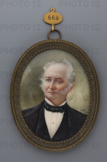 Portrait of an Elderly Man with Sideburns, by Jahn, Friedrich August fl. 1810–1894, painter. Miniature portrait 1894, Germany, bust: almost straight ahead, head three-quarters to the left. Subject: elderly man with gray hair and sideburns, gray eyes; wearing a white shirt, black tie, waistcoat, and frock coat. Hairstyle slicked back. Background: olive clouds/sky. Style: modernism. Materials/format: miniature, height 8.3 cm, width 6.3 cm. Frame: patinated brass with narrow rim and acanthus motif. Provenance note: repossession Jelenia Góra., An oval portrait in an ornate metal frame shows the bust of an older man with light gray hair and sideburns, fair skin with a slightly rosy complexion, and a composed expression; he wears a dark suit jacket and a white shirt with a black bow tie. The frame is a mottled brass or bronze color with decorative raised patterns and a small hanging loop at the top attached to a small oval tag; the background behind the figure is a muted greenish-gray. The v...