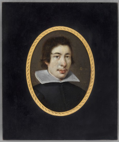 Portrait of a Young Man. Franz Kessler fl. 1580–1650, 1629. Miniature, height 9.8 cm, width 7.1 cm. Bust, 3/4 right. Hair c. brown, eyes grey. Dark olive caftan with white turndown collar; background olive green. Bronze rim binding with polished wood and braided motif on a narrow medallion rim. Inscription on front right: AEf: 21. | 1629 | FK. Reverse inscription noting Franz Kessler, activity 1613–1629 and birthplace Oppenheim. Genre: male portrait; style: miniature/self-portrait., An oval portrait of a young person with medium-length dark brown hair set against a dark background within a decorative gold oval frame; the person has a pale skin tone, visible facial features including dark eyes and slightly parted lips, and wears a black garment with a white, flat, wide collar; colors visible include black, gold, white, pale skin tones, brown, and subtle gray.