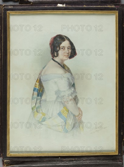 Portrait of Aleksandra, née Stecka, Princess Michal Radziwill. Painter: Jan Ksawery Kaniewski 1805–1867. Miniature, 1840. Standing figure shown from the right side, knee-deep, head three-quarters to the right. Dark brown hair parted in the middle; thin circular braids at the sides; decoration of rusty-red velvet ribbons at the back of the head; a gold chain with a la ferroniere medallion above the forehead; black velvet ribbon at the neck. White dress with a tyftic shawl with yellow and turquoise stripes on the left shoulder; arms lowered and folded. Background slightly watered. Rectangular narrow bronze frame decorated with a palmette, fluting and pearls; in a lockable case of dark purple leather. Inscription: IX Kaniewski/m. in Rome 1840. Dimensions: height 29.2 cm, width 22.3 cm. Subject: Aleksandra Radziwill, née Stecka 1796–1864, wife of Michal IX Radziwill 1778–1850., A framed portrait of a woman shown from the waist up turned slightly to the side, wearing a white off-the-shoulde...