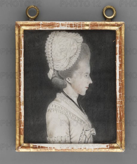 Amalia Eleonora von Solms-Braunfels 1734–1811, princess of Anhalt-Bernburg-Schaumburg; miniature portrait, ca. 1800, Germany. Waist-length right-profile portrait: fair hair covered with a white bonnet, blue eye; black ribbon around the neck, white dress; black background. Frame: wood. On the back of the mounting an inscription: Amalie Eleonore/Furstin zu Anhalt-Bernburg=Schaumburg Tochter/Der Fursten Friederic/Wilhelm zu Solms=Braunfels and two labels one with a fragment of a seal. A card with the inscription: Amalie Eleonore./ Furstin zu Anhalt-Bernburg=/Schaumburg/Geboren Prinzesin von Solms-/Braunfels/Geboren den 22 ten November 1734./ Gestorben den.1810. Miniature, height 11.4 cm, width 9.3 cm. Creator unknown amateur. Subjects: women, rulers; styles: portraits, profiles, female portrait, foreign miniatures., A framed portrait of a woman shown in profile against a dark background, the woman wearing a light-colored dress with decorative trim and a bow at the front, and a tall, textu...