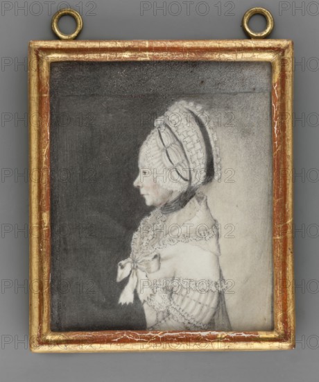 Caroline Katherina von Birkenfeld 1699–1785, third wife of Friedrich Wilhelm I zu Solms-Braunfels. Unknown artist. Ca. 1800. Miniature portrait, profile of a woman in headgear and costume; height 11.7 cm, width 9.1 cm., A framed portrait of a person in profile facing left, depicted in pale tones against a darker background; the person wears a white, lace-trimmed bonnet with decorative bands and a dark ribbon tied under the chin, and a light-colored shawl or dress with lace edging and a bow at the front; the drawing is mostly in shades of gray, black, white, and pale skin tones, and the rectangular frame is gilded with worn gold and reddish-brown areas with visible cracks and two circular hanging rings at the top.
