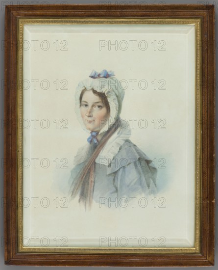 Portrait of Ludwika Hilbertz Soubirau, beloved nurse of Aleksandra Potocka, daughter of Stanislaw Septym and Katarzyna née Branicka; after Thomas Lawrence 1769–1830 by an unknown painter; miniature, 1840, Rome; height 24.0 cm, width 18.5 cm; costumes, women, female portrait, headgear., A framed watercolor portrait of a woman wearing a bonnet and cloak, with a pale face and dark hair peeking from beneath the bonnet; the bonnet is light with a small bow on top and ruffled trim, and a ribbon tied under her chin. The cloak and dress are in soft blue-gray tones with layered collars and ruffled details, and a long brown scarf or hair strand drapes down over the front. The background is a pale, off-white wash, and the portrait is set within a gold inner frame and a wider brown outer frame showing wood grain. Colors visible include white, cream, pale blue, blue-gray, brown, gold, and flesh tones.