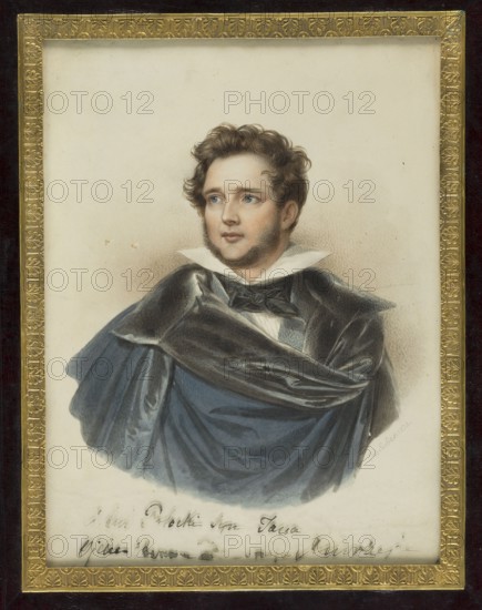 Artur Stanislaw Potocki from Krzeszowice 1787–1832. Bel Arthur, son of Jan and Julia née Lubomirska. Portrait by Johann Nepomuk Ender 1793–1854, painter. Miniature portrait, painted in Vienna, 1832. Subject: aristocratic male in costume male portrait. Dimensions: 22.7 × 17.0 cm., A framed portrait of a young man with light skin and curly brown hair, shown from the chest up, wearing a dark blue cloak with a shiny black draped collar and a white high collar beneath; his face has light stubble and blue eyes looking slightly to the side, and the portrait is set against a pale beige background with a decorative gold inner frame and a dark outer frame, showing colors including brown, blue, black, white, gold, beige, and hints of reddish tones in the hair and cheeks.
