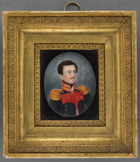 Portrait of a colonel of the Russian army, unknown painter, miniature, height 7.3 cm, width 5.8 cm; uniforms; orders: Order of St. Vladimir 3rd class, Polish Badge of Honour; 1830; male portrait of a soldier., A framed oval portrait of a man in a military uniform is centered within an ornate rectangular gold frame; the frame has decorative embossed patterns and a ring hanger at the top, and shows areas of wear and small dark spots. The portrait shows a man with brown hair and a trimmed mustache, fair skin, and a neutral expression, wearing a dark blue coat with a bright red front panel and high collar, and gold epaulets with a dotted pattern on his shoulders; the background behind him is a muted gray with subtle texture. Visible colors include gold, red, dark blue, gray, brown, black, and flesh tones.