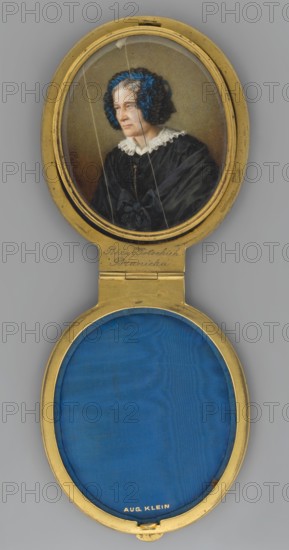 Portrait of Róza Potocka 1760–1862, also known as Antoniowa Potocka and Grzegorzowa Branicka; miniature portrait by Paul W. active ca. 1860–1880, painted in 1860; watercolor miniature, height 9.4 cm, width 7.7 cm; depicts aristocratic costume and headgear, female portrait., An oval gold locket opened to show a painted portrait in the top half and a blue fabric interior in the bottom half; the portrait depicts an older woman with pale skin and grayish hair wearing a black dress with a white lace collar and a dark bow at the front, and a dark bonnet or headpiece decorated with bright blue ribbons framing her face, set against a muted brown background; the locket frame is gold with a hinge connecting the two halves, and the lower compartment shows a deep blue fabric lining surrounded by the gold metal.