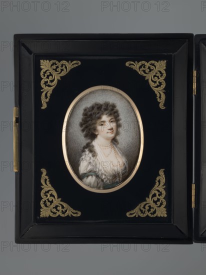 Portrait of Julia Potocka, née Lubomirska 1766–1794. Giuletta la bella. After Joseph Grassi 1757–1838 and Wincenty de Lesseur 1745–1813; unknown painter. Half-length, three-quarter figure to the right. Aristocratic female portrait: dark curled hair with woven string of pearls, four-strand pearl necklace, corseted robe chemise dress, white fichu, blue bows on the sleeves. Background grey, lightened around the figure. Inscription/title Giuletta la bella. Binding: narrow brass border in a polished mahogany wooden frame with stylized brass floral ornaments in the corners. Dated 1780, Poland. Miniature; height 7.1 cm, width 5.3 cm., A framed oval portrait of a woman set in a rectangular black case with hinged edge, the frame decorated at the corners with ornate gold filigree motifs; the portrait shows a woman with dark curly hair and a pale complexion, wearing a white ruffled dress with visible folds and a few strands of pearls around her neck, her expression neutral and gaze slightly turne...