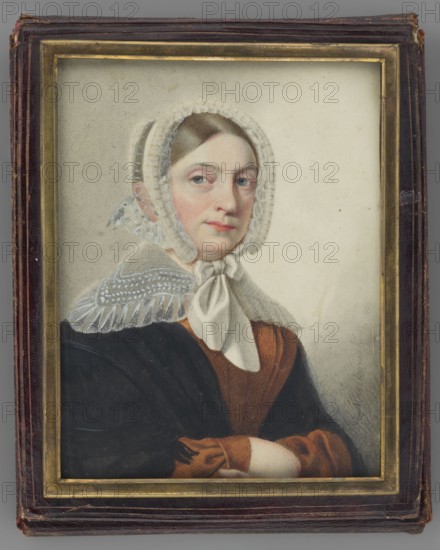 Portrait of a Woman in a White Bonnet, Maszkowski, Jan Kanty 1794–1865 painter. Watercolor miniature, 1840. Subject: elderly woman, torso three-quarters facing right; ash-blond hair parted in the middle and combed smoothly over the temples; white tulle bonnet tied under the chin; wide turn-down transparent white collar with embroidery, trimmed with a ruffle; light brown dress; black shawl with fringes on the shoulders; both arms folded over each other. Background: light grey, lightly outlined with rubbed-off pencil. Inscription along the right: Maszkowski. Frame: gilded bronze strip in a dark cherry leather case frame. Dimensions: height 15.2 cm, width 11.5 cm. Polish miniature; portraits, women, headgear., A framed portrait of a woman wearing a white lace bonnet tied under her chin and a white scarf, with brown hair peeking at the forehead; she has a pale complexion with pinkish cheeks and light-colored eyes and is looking slightly to the side; she wears a brown dress with a darker br...