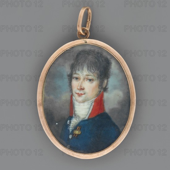 Seweryn Potocki 1762–1829, Grand Crown Carver, senator, brother of Jan Podróznik. Bust portrait, three-quarters left. White cravat and jabot, short hair curled à la Titus, dark sideburns, navy blue uniform tailcoat with a ribbon with orange and black stripes, high red collar with white piping. Miniature, height 3.7 cm, width 2.9 cm. 1800, Poland. On the reverse a small photo of a young girl. Unknown creator amateur., An oval pendant with a metallic gold-toned frame and bail contains a painted portrait of a young person with pale skin and short wavy dark hair, wearing a high white collar and a blue coat with a red collar accent; the face shows light pinkish cheeks and neutral expression, the background is a soft cloudy mix of gray and muted blue-green, and the pendant frame shows subtle worn areas and a small darker blemish near its top.