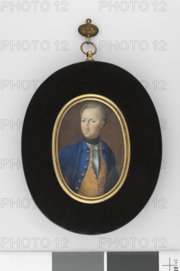 Charles XII, King of Sweden 1682–1718, unknown artist, male portrait to the waist, turned left, ruler, soldier uniform, silver cuirass, foreign miniature, Hesse Germany — Half-length to the hips, 3/4 view to the left. Grey hair, blue eyes. Black handkerchief at the neck, silver cuirass with yellow-orange vest over it, sapphire tailcoat with orange buttons, navy blue hat held under the left arm. Background chocolate brown. Frame: bronze and wood. 1705. Miniature; height 7.2 cm, width 5.0 cm., An oval pendant with a black outer frame and a gold inner oval surrounds a small painted portrait of a young person wearing a blue coat with gold buttons, a tan vest, and a dark neck scarf, the person has pale skin and light hair pulled back, and the pendant is topped by a small brass hanging fixture and ring; colors visible include black, gold, blue, tan, dark gray, pale skin tones, and brass.