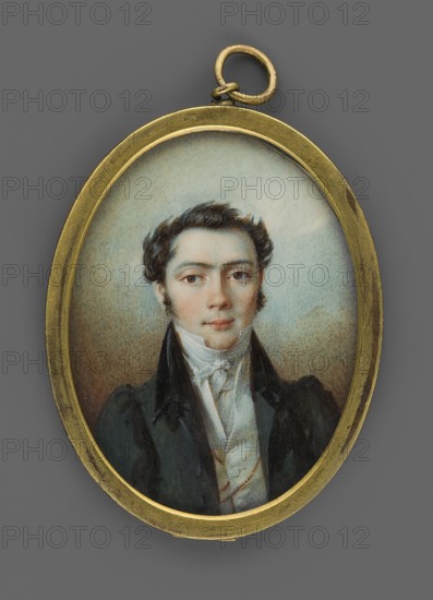 Portrait of a young man in a black tailcoat, en face portrait, male, nobility, Polish miniature, unknown artist, 1826, miniature; height 5.2 cm, width 4.0 cm., An oval pendant with a gold-colored metal frame and loop contains a painted miniature portrait of a young man shown from the chest up; he has dark brown wavy hair, fair skin with a slight rosy tint, and dark eyes with a neutral expression. He wears a high-collared white shirt and cravat beneath a dark coat with broad lapels, and the background inside the pendant is a soft, muted mix of pale blue and beige tones while the outer area around the pendant is a medium gray.