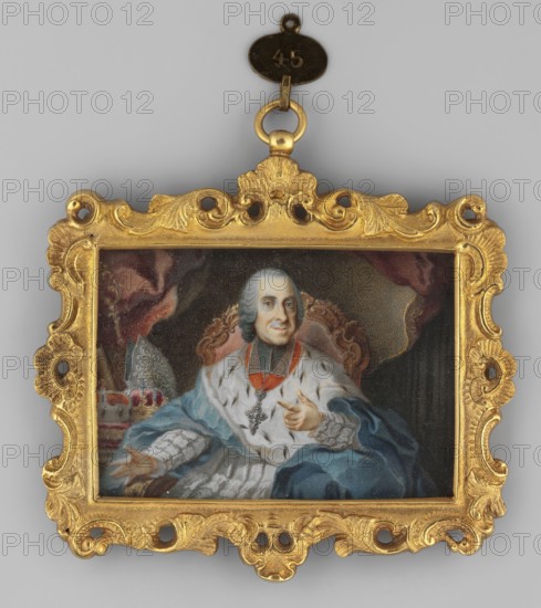 Bishop Joseph Ignaz Philipp von Hessen-Darmstadt 1699–1768, son of Ernest Ludwig and Maria-Theresa de Croy; painted by Nilson, Johann Esaias 1721–1788. Oil miniature 1790, Germany, height 5.0 cm, width 7.1 cm. Seated in an armchair, almost straight ahead, hair gray, wearing a blue cloak with ermine over a white surplice richly decorated with lace, a gold bishop's cross on the chest; knee-length portrait showing bishop's vestments mantelletta, cope, rationale, powdered wig; background shows a fragment of an interior with a curtain. Binding richly decorated with stylized plant motifs mainly acanthus, gilt bronze., A small rectangular painted portrait set in an ornate carved frame with a hanging loop at the top shows a seated man wearing a powdered wig and richly decorated robes; he has a pale face with a faint smile and is gesturing with one hand while the other rests on his lap, and he wears a jeweled cross and a sash. The background includes draped fabric in dark red and brown tones an...