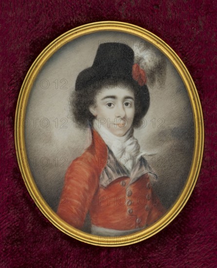 Portrait of a man in horseback riding or hunting attire. Half-length figure facing right. Black hair in small curls obscures the top of the forehead. Black high-brimmed hat with a red cockade and a white ostrich feather. A white cravat tied with a bow, a red double-breasted tailcoat with lapels, and a wide white belt at the waist. Background: dark clouds at the bottom, light pearl clouds at the top, all in shades of black, white, and red vermilion. Miniature, c. 1800; height 6.1 cm, width 5.1 cm. Józef Choynowski 1833–ca.1915 attributed. Binding: a narrow, profiled rim of gilded bronze set in a rectangular slat covered with cherry plush. Subjects: men, hats, hunters, feathers, headgear, costumes; portrait en three-quarters, male portrait., An oval framed portrait set against a deep burgundy textured background shows a young person with pale skin and dark curly hair wearing a tall black hat adorned with a small red ornament and a white plume; they wear a high white cravat and a red coat...