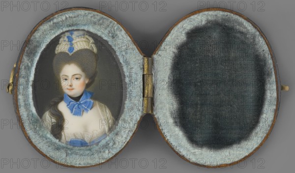 Portrait of a woman in a gray wig. Unknown artist. Aristocratic female three-quarter portrait, bust slightly right, head turned left. Tall gray wig with a white headdress at the top; a long wavy strand of hair falls over the right shoulder. At the neck a black scarf with a light sapphire ribbon tied in a bow. White satin low-cut dress with lace at the bodice and a large light sapphire bow below. Dark gray background. Oval case of dark brown leather, lined with blue velvet inside, closed with a hook. Ca. 1770. Miniature, height 5.6 cm, width 2.9 cm., An open oval case with a hinged center shows a small painted portrait on the left side and a padded interior on the right; the case interior is lined with pale bluish-gray plush fur around each oval opening and darker gray fabric in the central recessed areas, while the exterior edges show brown leather and a small brass hinge and clasp. The painted portrait depicts a person with pale skin, dark brown hair styled high and long with a cream ...