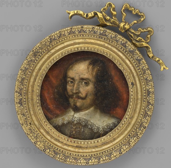 Portrait of a Man, unknown artist, portrait en trois-quarts, copy, male portrait, foreign miniature; bust three-quarters left; brown shoulder-length curls with sparse strands on a balding forehead; small beard and upward-curled mustache. Wearing a wide turn-down collar trimmed with lace and an ash-grey doublet with gold embroidery. Background with folds of rusty drapery. Round recessed slightly profiled bronze sheet frame embossed with pearlescent ornaments, palmette pattern, and a bronze bow at the top. Dated circa 1850–1690 miniature., A round painted portrait set in an ornate circular frame with a decorative bow at the top, showing a person with shoulder-length dark hair, a mustache and small goatee, wearing a white lace collar and a dark garment, against a reddish-brown background; the frame and bow are gold in color and the surrounding background is gray.