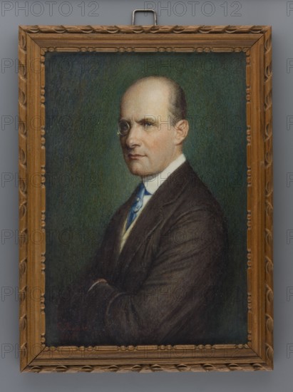 Portrait of a Man with a Monocle, G. Burger, 1918. Miniature, height 12.2 cm, width 8.4 cm. Half-figure, three-quarter left. High forehead, short sparse smoothly combed greyish-brown hair at the back of the head. Gold-rimmed monocle in the left eye, clean-shaven face. White collar, blue tie with two gold-set pins, cream vest, grey-brown jacket. Arms folded. Background dark green. Quadrangular profiled and ornamented unpolished walnut frame. Style: modernism. Location of creation: Germany., A framed painted portrait of a man shown from the waist up with arms crossed, wearing a dark brown suit jacket, a white shirt collar, and a blue tie; his head is bald on top with short hair at the sides and he wears a small round eyepiece over one eye, his expression appears neutral, and his skin tone is light; the background is a textured green with darker and lighter variations; the frame is wooden with a carved decorative pattern in brown and there is a metal hanger at the top.